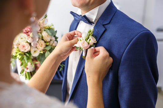A lady positioning a boutonniere on a gentlemen's lapel.